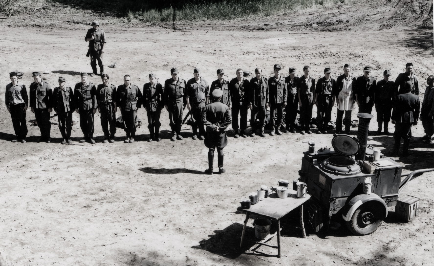 Military assembly — soldiers lined up in an open field with an officer addressing them