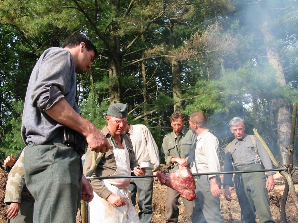 Soldiers around a campfire spit roast