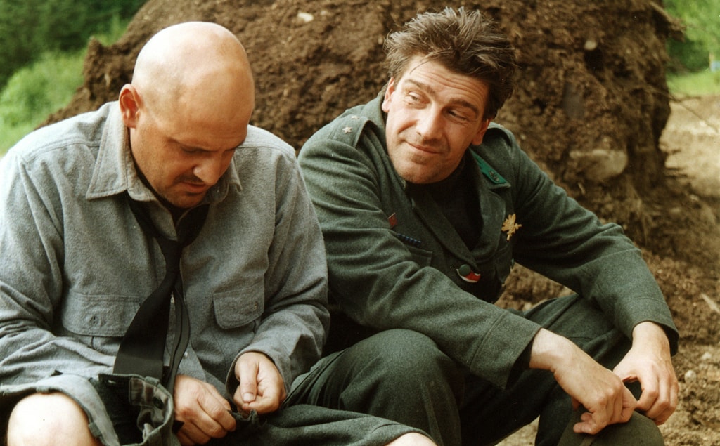 Two men resting against a dirt mound